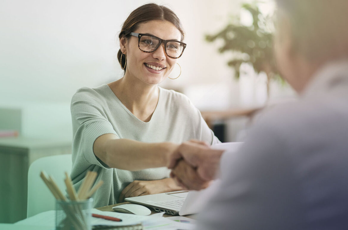 Female accounting and tax firm owner shaking hands with her business partner