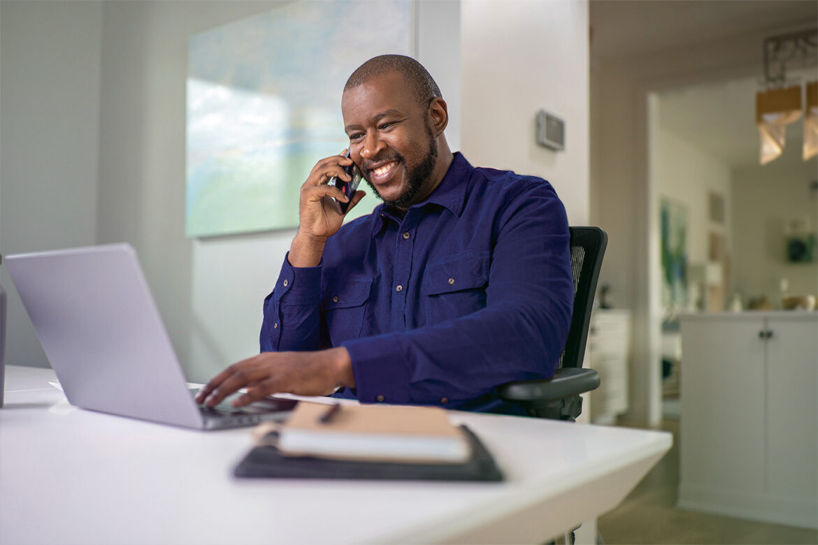 Male sitting at his desk in a home office searching for personal banking products on his laptop