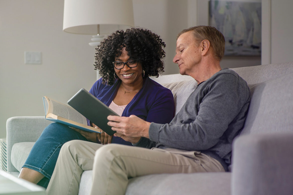 A couple at home on their couch reviewing their personal high-yield certificate of deposit accounts on a tablet